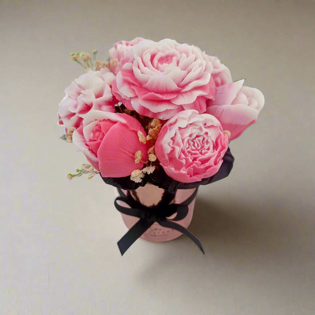 Pink flower arrangement in a small pot with a black ribbon on a light background