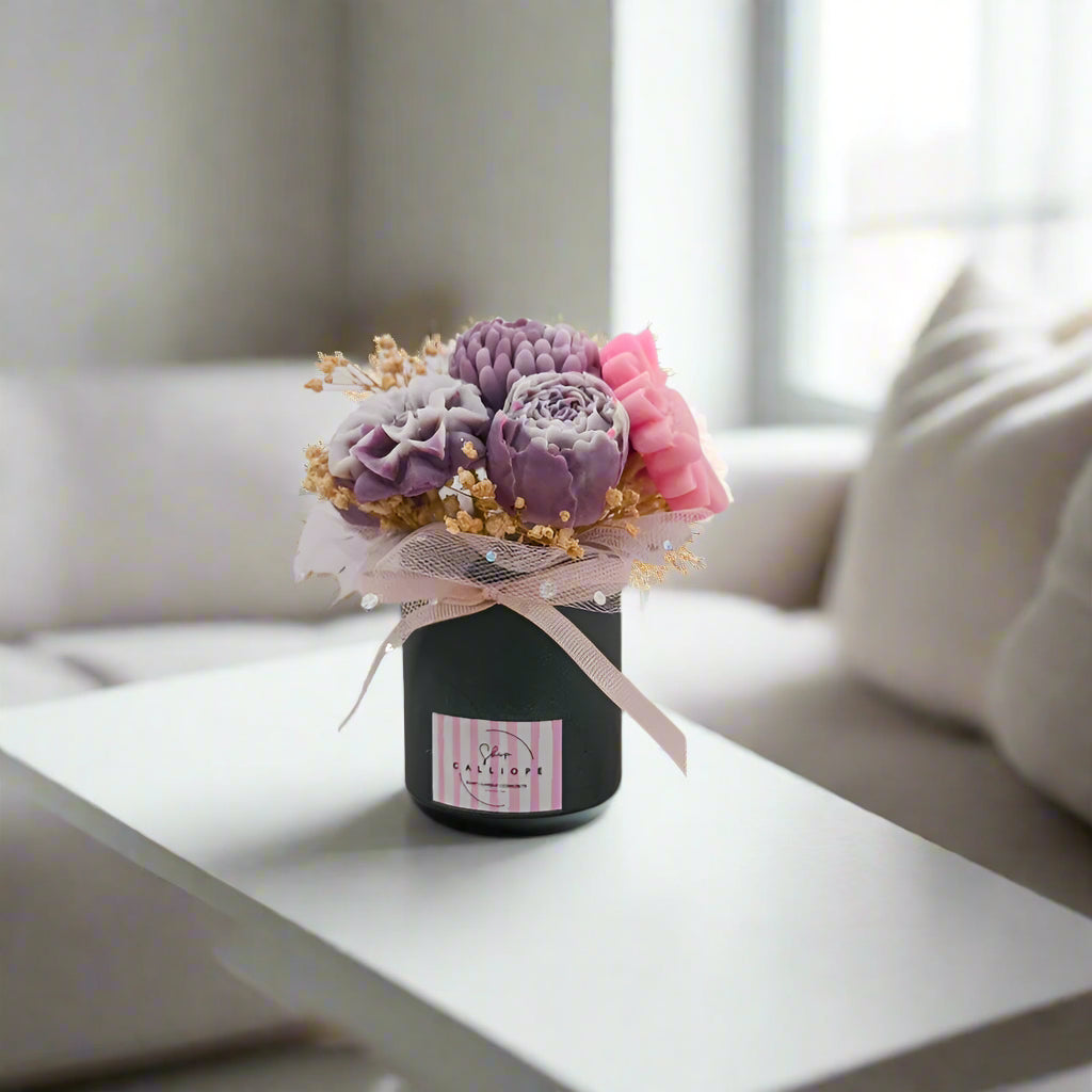 Small bouquet of flowers in a black box with a pink ribbon on a white background
