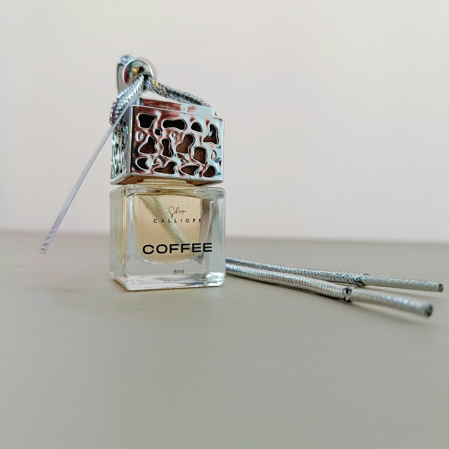 Coffee-scented car diffuser with decorative top on a plain background