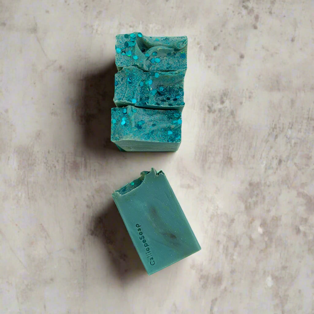 Two turquoise soap bars with glitter on a white background