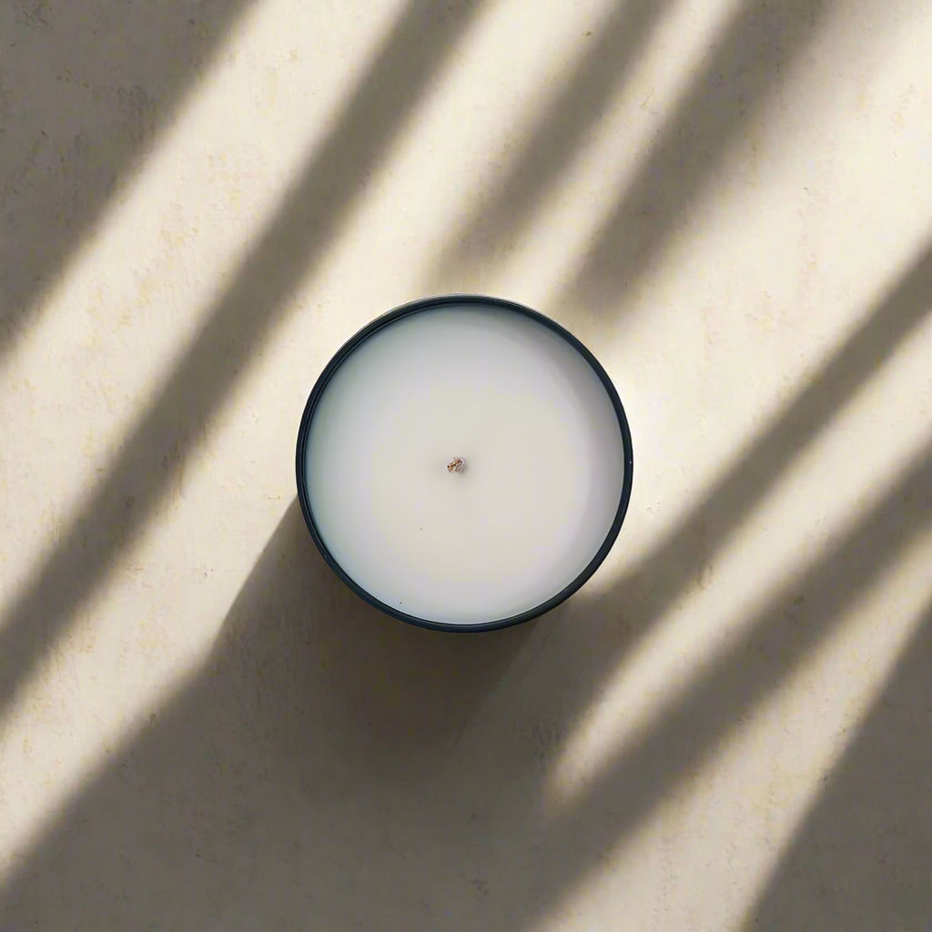 Small white candle with a dark rim on a light gray surface