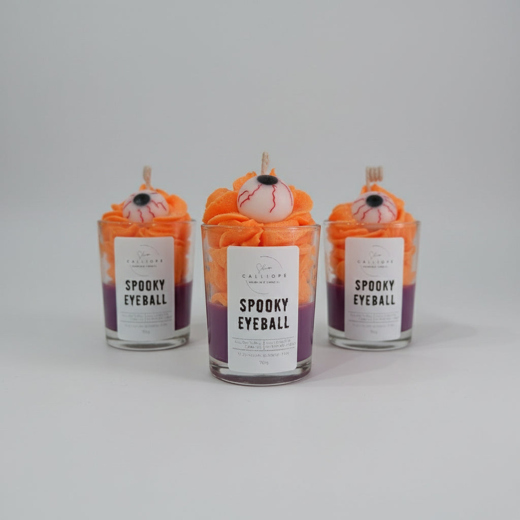 Three 'Spooky Eyeball' candles in glass jars on a gray background