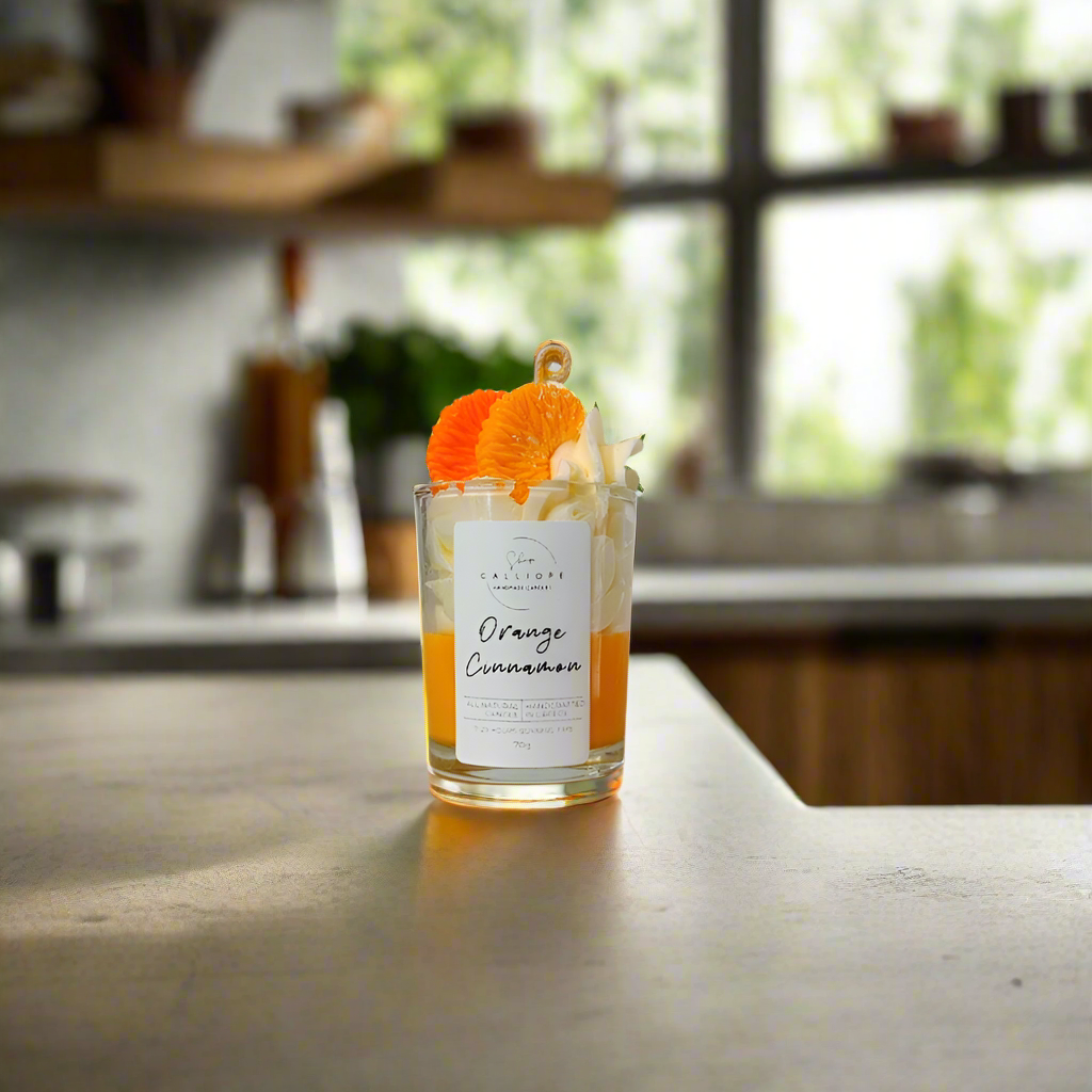 Candle labeled 'Orange Cinnamon' on a kitchen counter with a blurred background