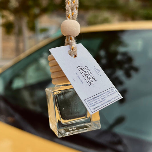 Car air freshener with a tag on a car dashboard, blurred outdoor background