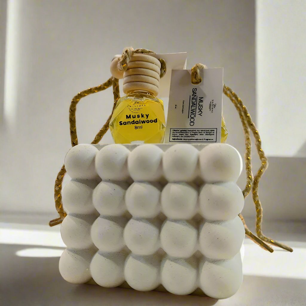 Musky sandalwood scented car diffuser with decorative top on a plain background