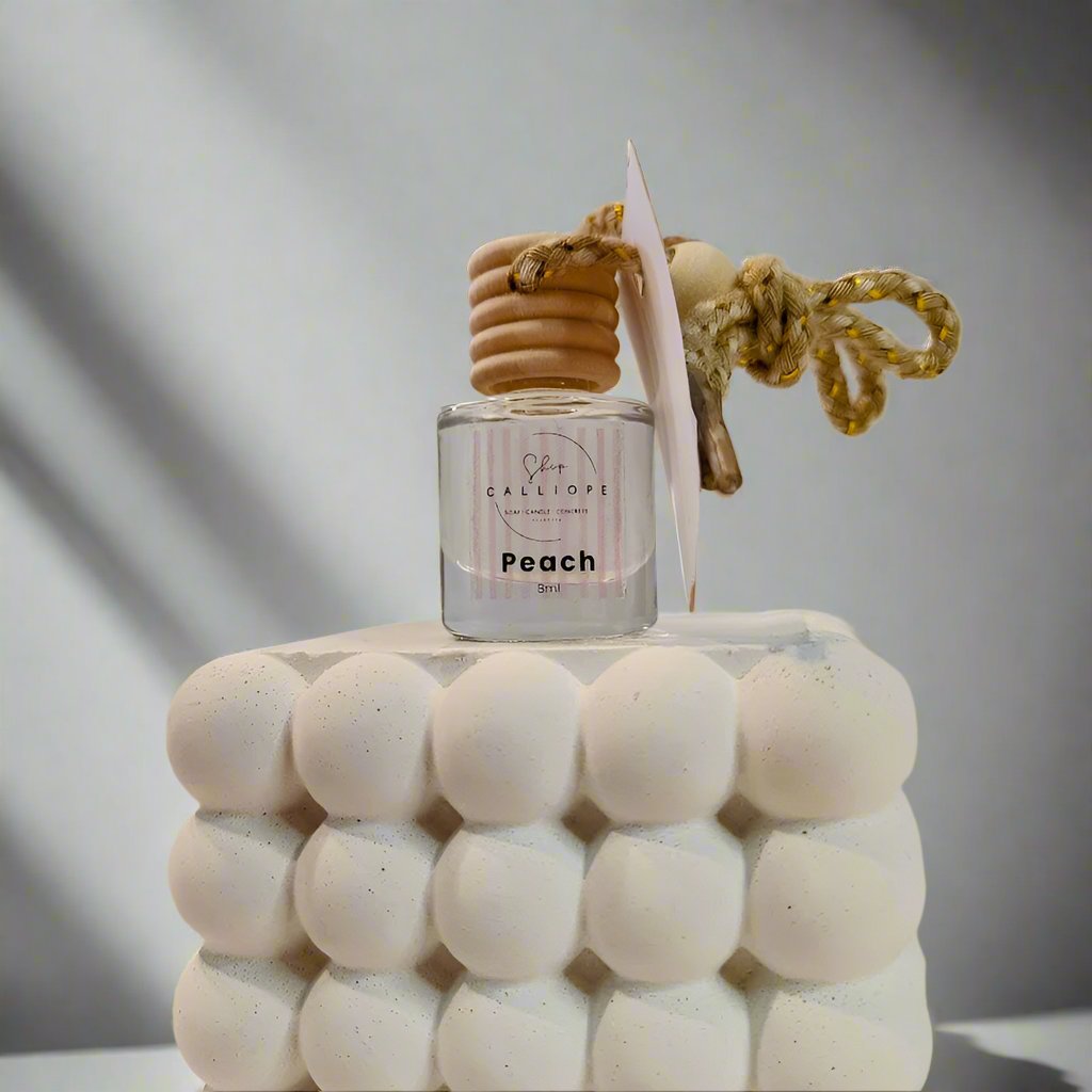 peach scented car diffuser with decorative top on a plain background