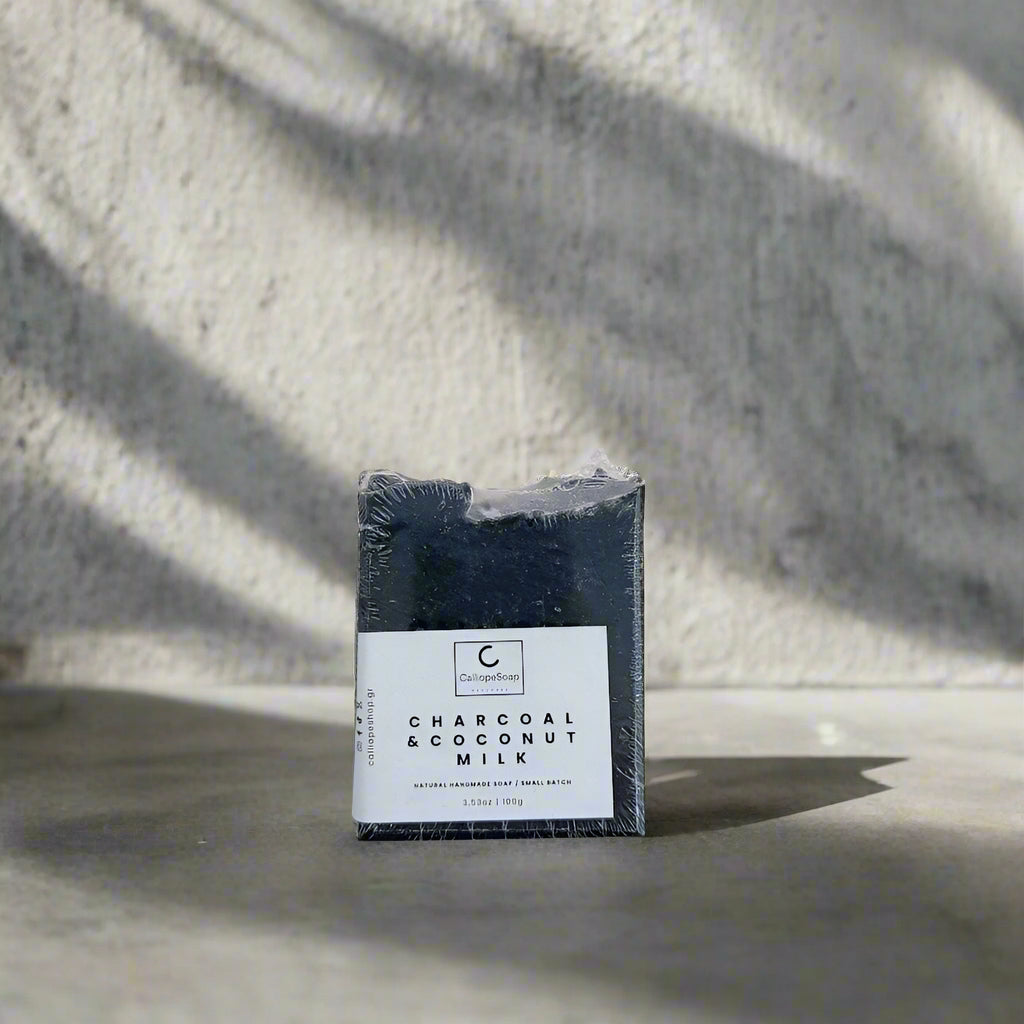 Bar of charcoal and coconut milk soap in packaging on a light gray background