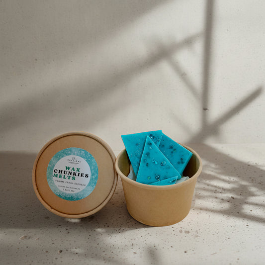 A box of blue wax melt chunkies placed inside a brown paper container, with a label that reads 'Wax Melts Chunkies'.