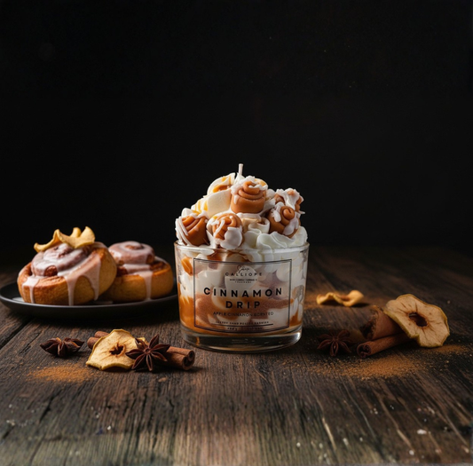 Candle labeled 'Cinnamon Drip' with cinnamon rolls and spices on a wooden surface
