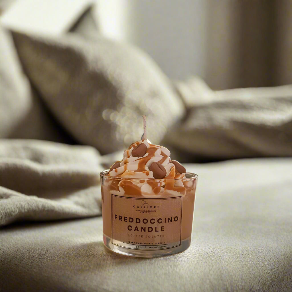 Freddoccino candle with a lit wick on a soft surface
