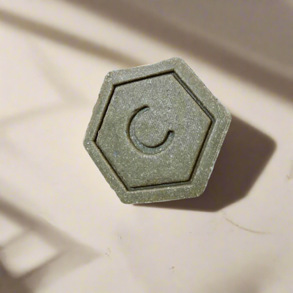 Hexagonal green solid shampoo on a beige surface