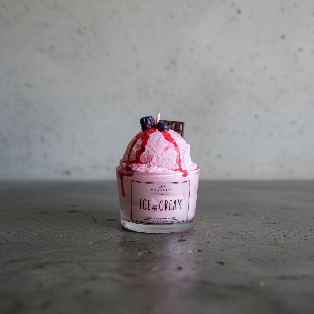 Pink ice cream candle in a container with berries and chocolate on a light surface