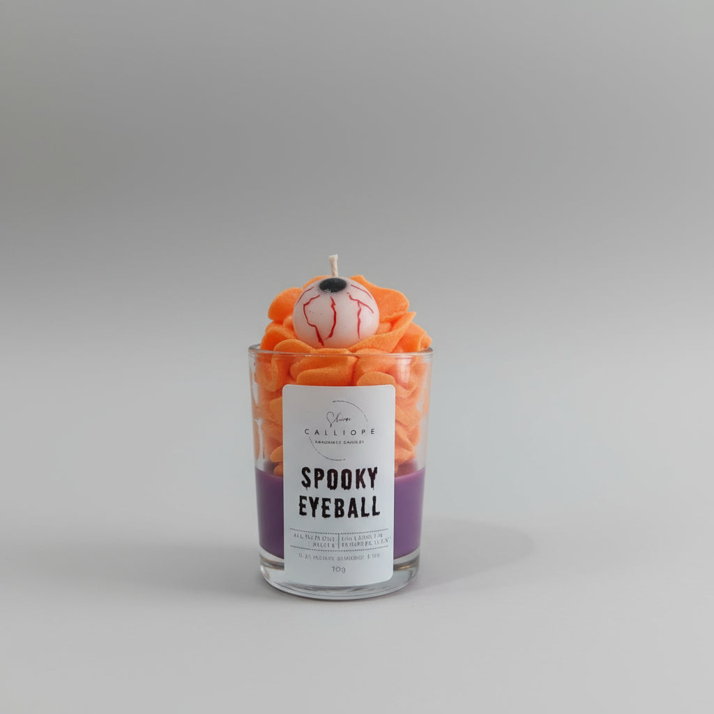 Candle labeled 'Spooky Eyeball' with decorative elements on a white surface.