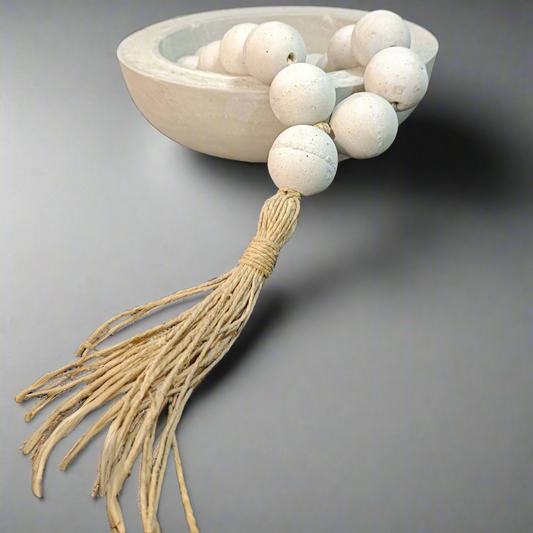 Decorative item with white beads and tassel on a white background