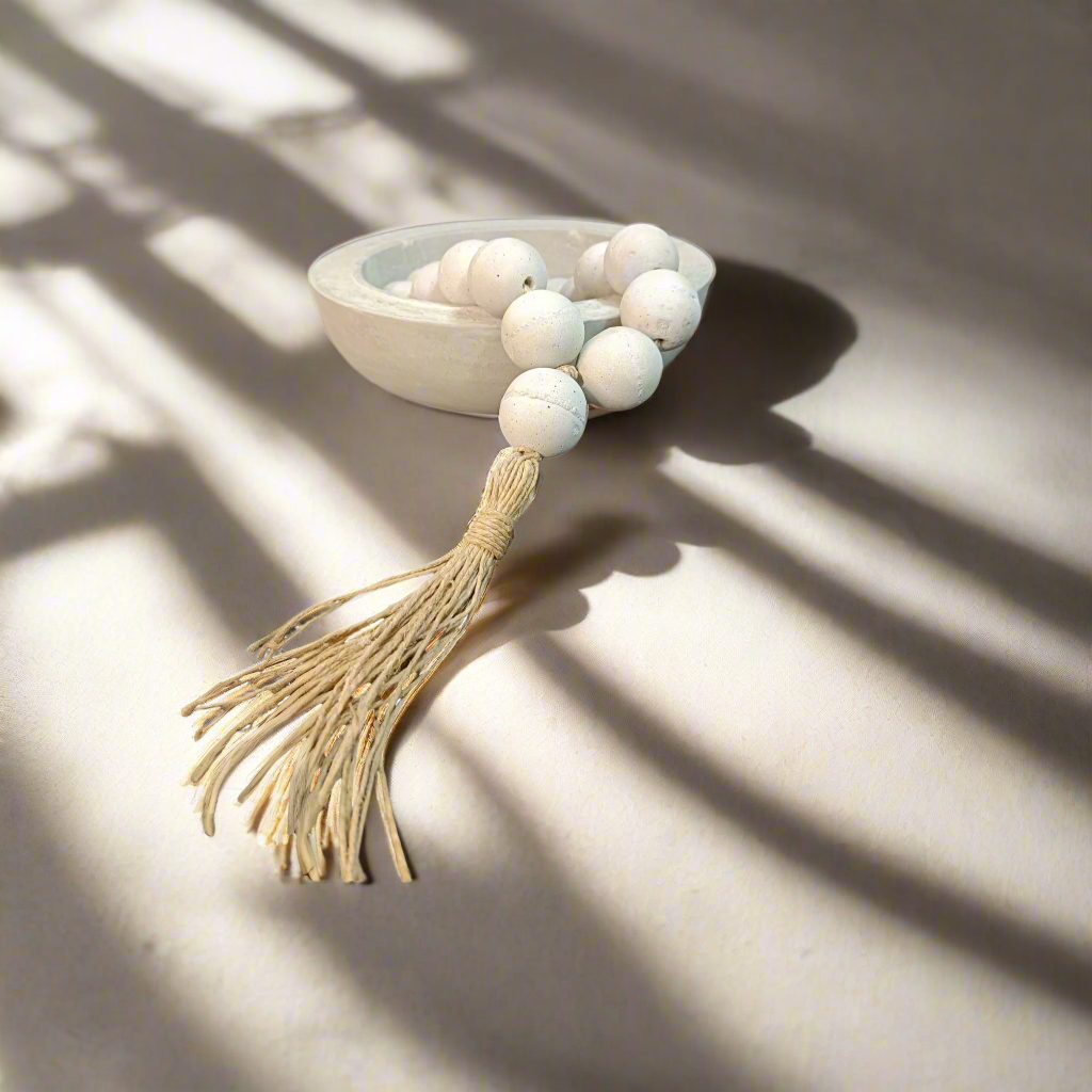 Decorative item with white beads and a tassel on a white background