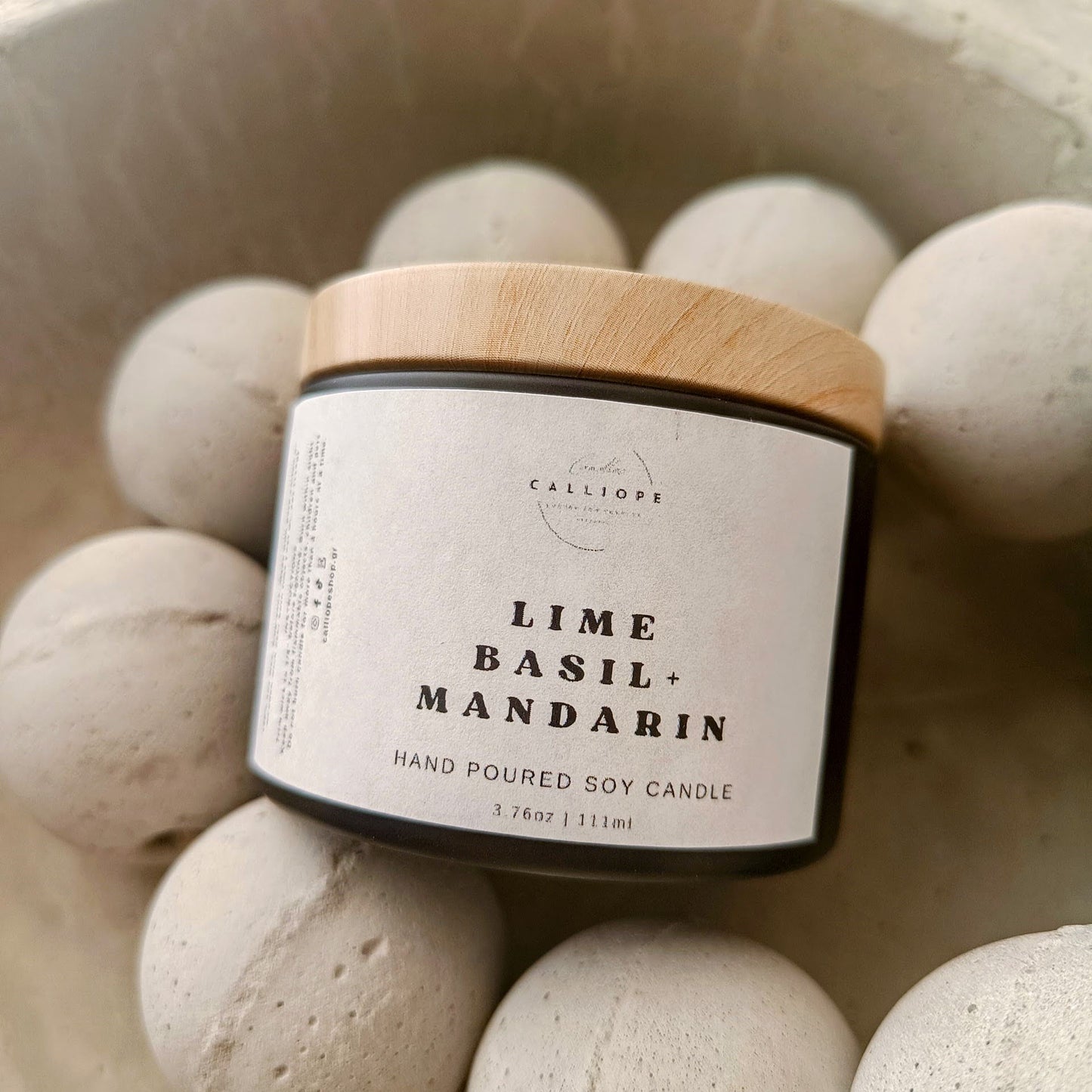 A set of four black tins with lids containing soy candles in different fragrances, labeled respectively as Orange Patchouli, Vanilla, Peony, and Amber.
