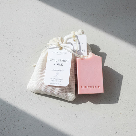 Pink soap bar with a drawstring bag labeled 'Pink Jasmine & Silk' on a light gray surface.