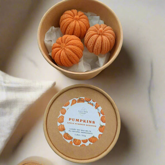 Round container with orange pumpkin-shaped wax melts on a light beige background