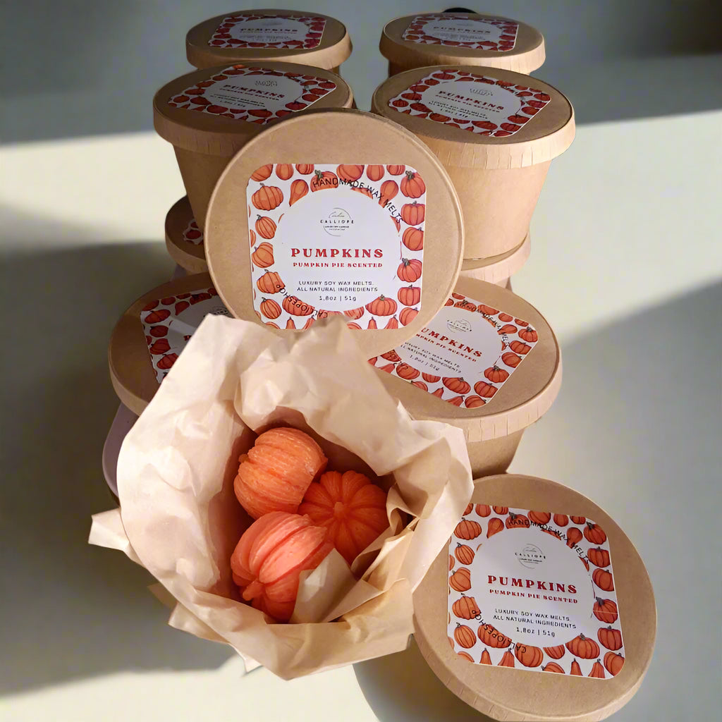 Pumpkin-shaped wax melts in a cardboard container with decorative labels on a textured surface.