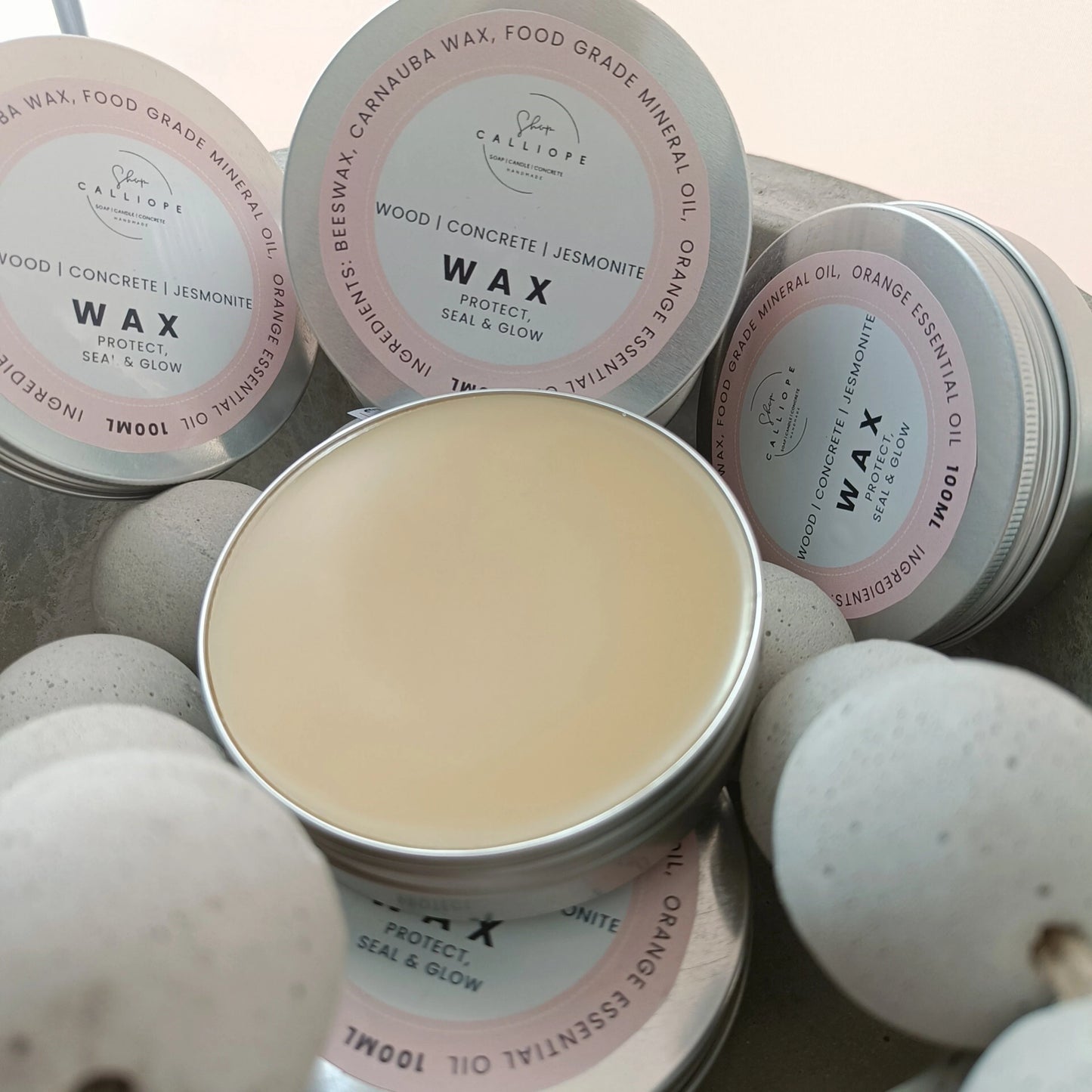 Tins of wax with visible labels on a textured surface