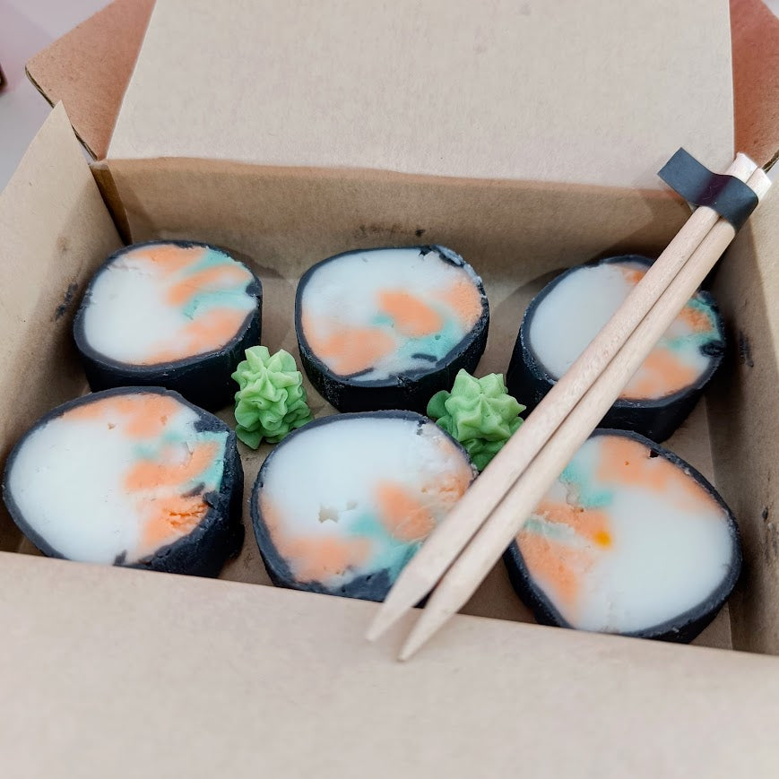 Sushi rolls with white and orange filling in a cardboard box with chopsticks.