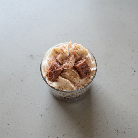 Tiramisu dessert in a glass container on a light surface