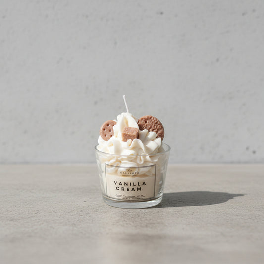 Αρωματικό κερί Vanilla Cream της Calliope σε γυάλινο ποτήρι, με φόντο ακατέργαστο τσιμέντο.