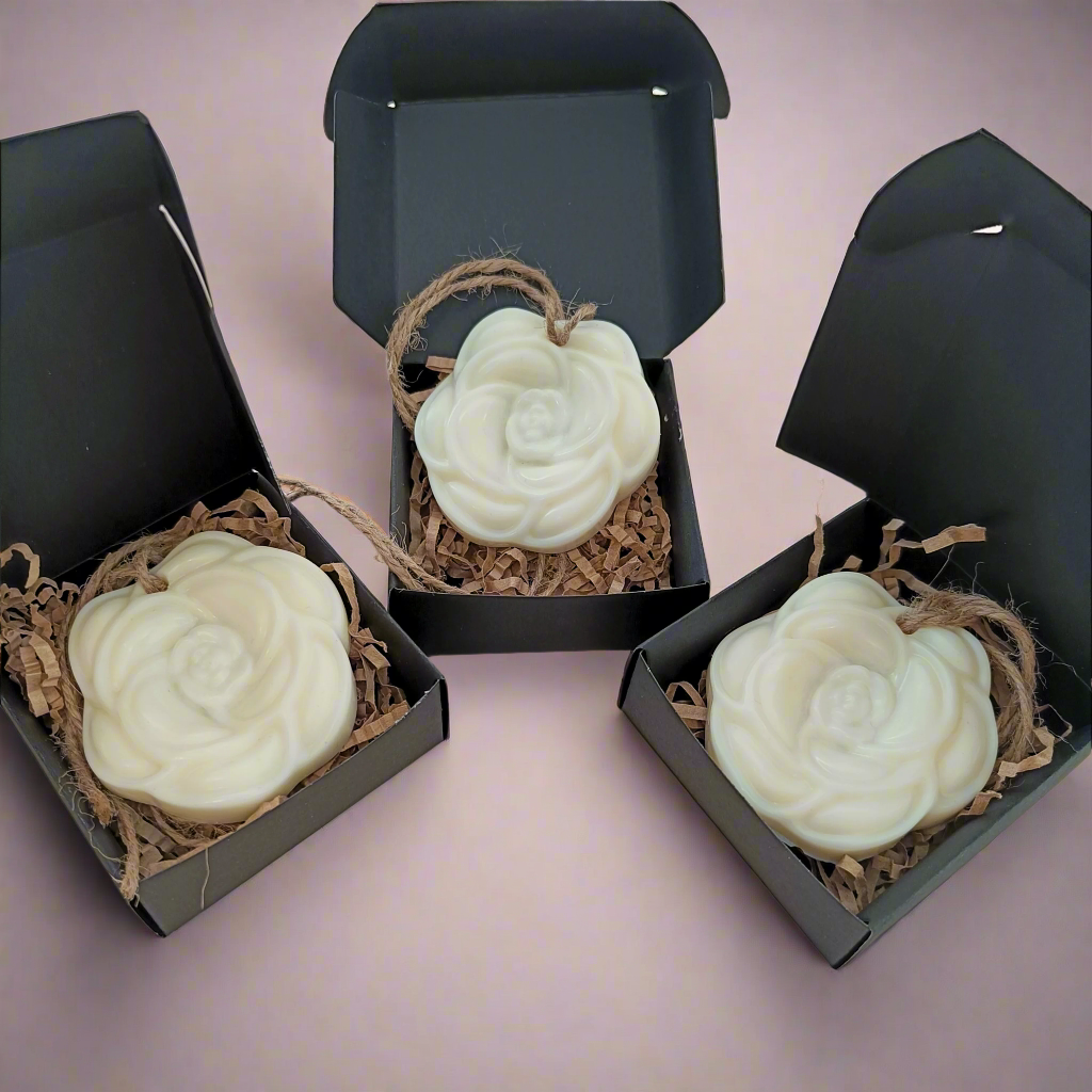Three white wax tarts in black packaging with twine, designed to resemble flowers.