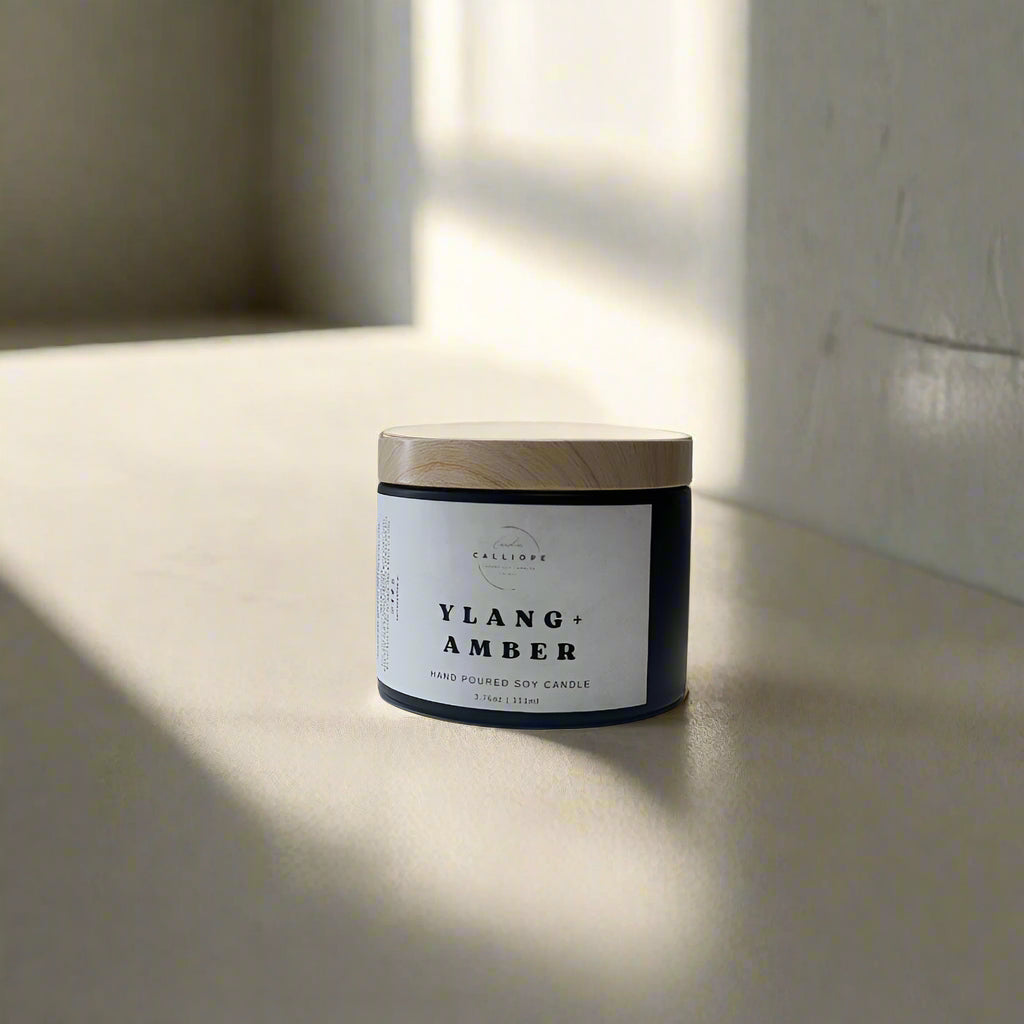 Candle jar labeled 'Ylang Amber' on a white surface with a light gray background