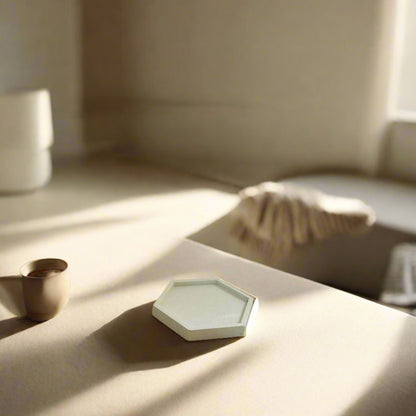 A minimalistic hexagonal porcelain dish with a plain white color, displayed in a bright interior setting, possibly being used as a decorative piece.