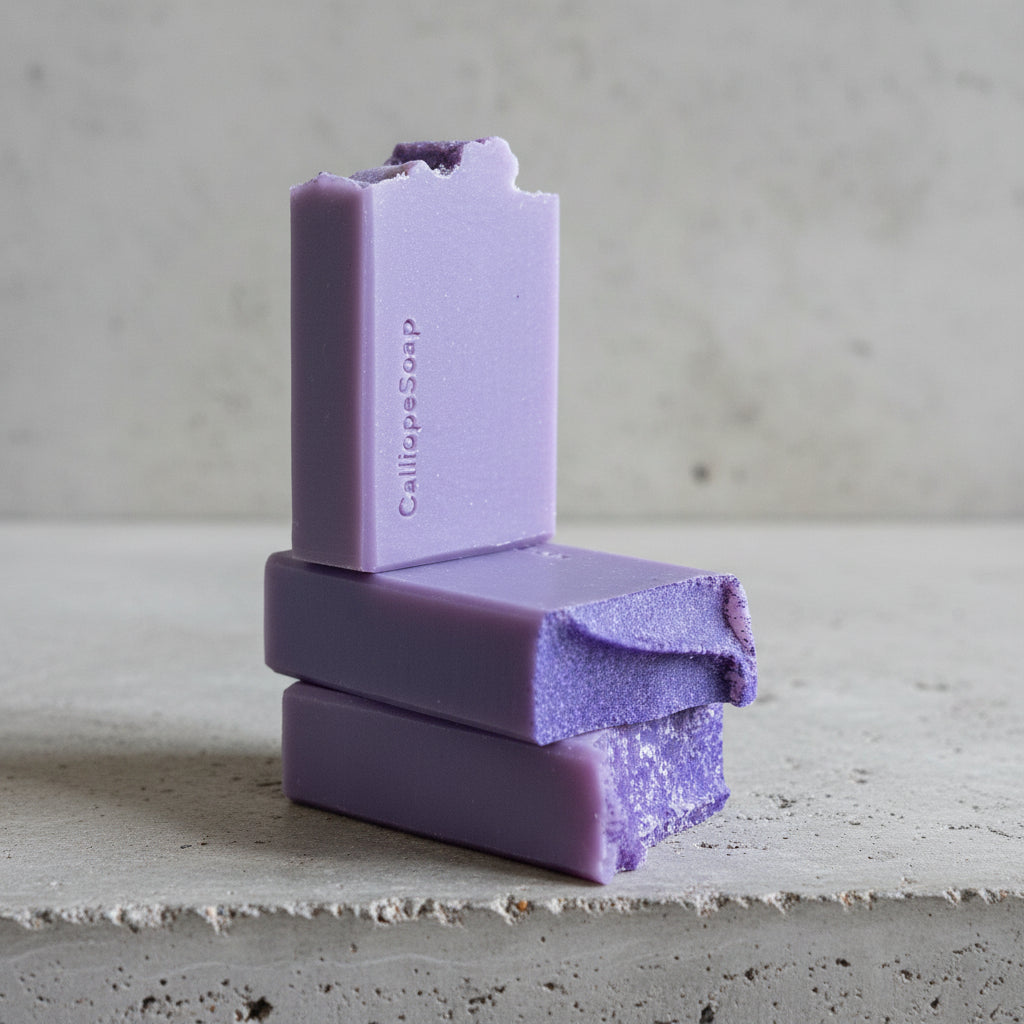 Three purple soap bars stacked on a grey surface with a blurred background