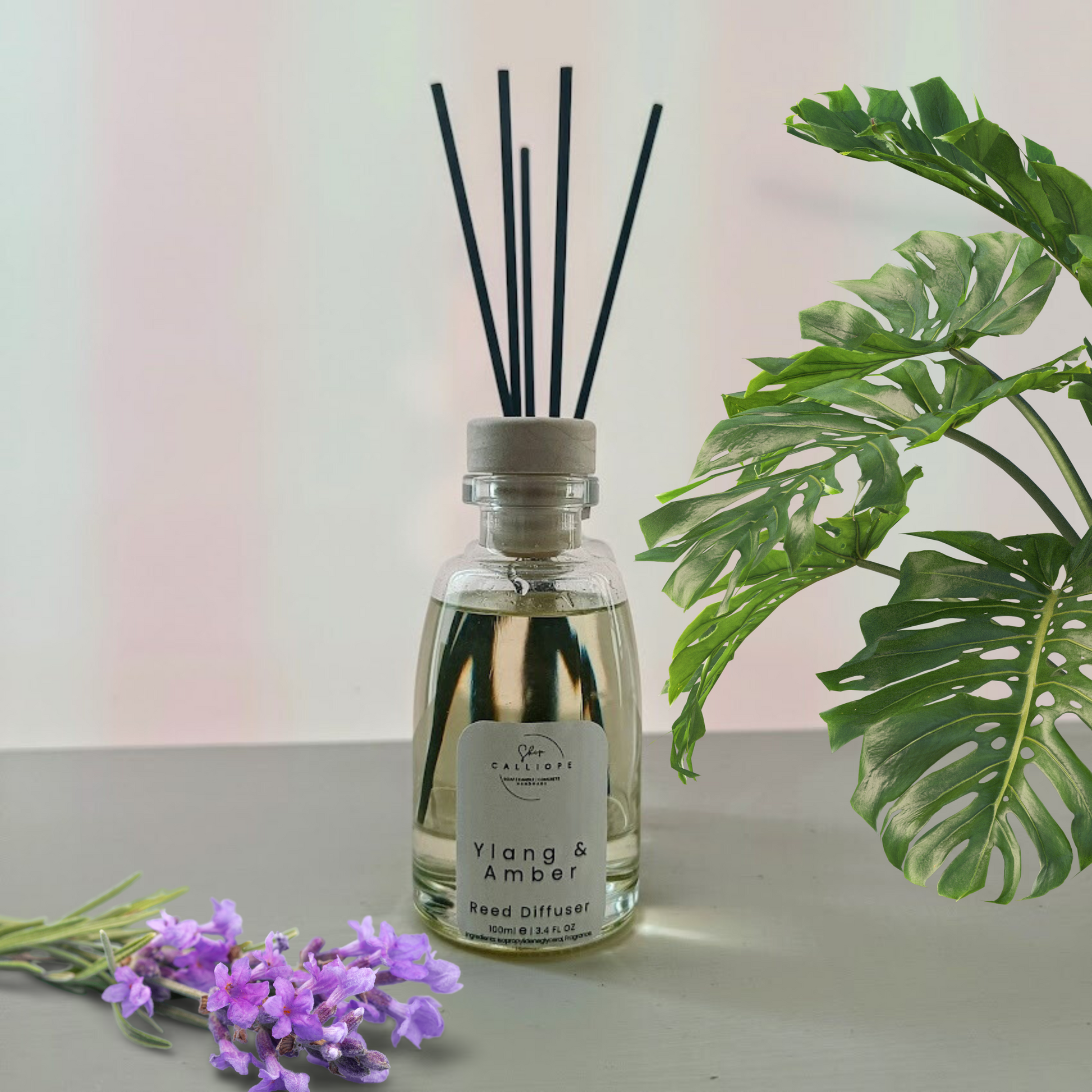 reed diffuser με άρωμα ylang & amber δίπλα σε διακοσμητικά λουλούδια
