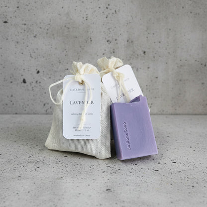 Purple soap bar with a drawstring bag labeled 'Lavender' on a white surface.