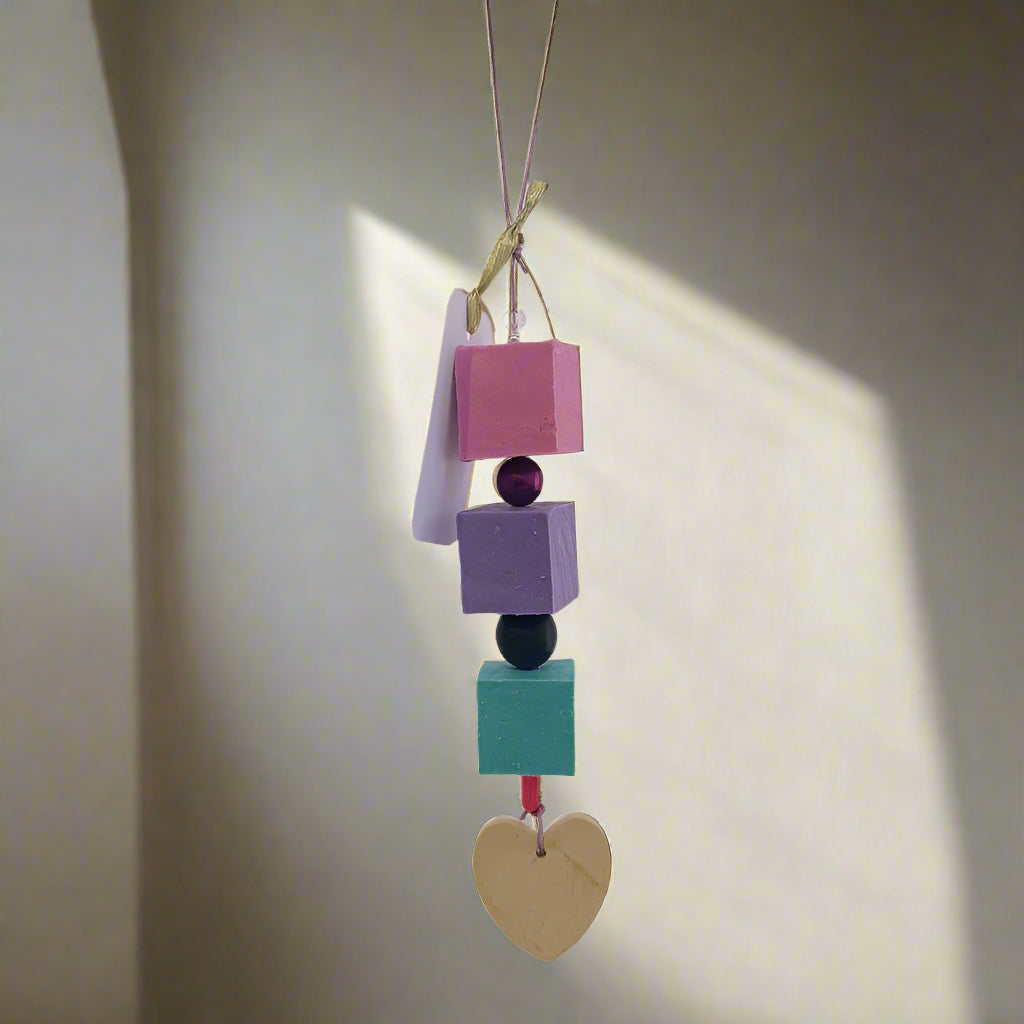 Colorful soap beads with a heart on a light purple background