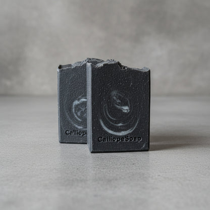 Two black soap bars with 'Calliope Soap' branding on a white surface.