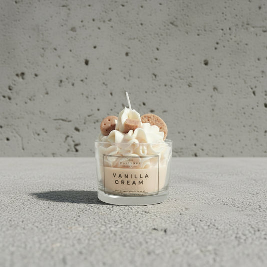 Χειροποίητο κερί Vanilla Cream σε γυάλινο ποτήρι, φωτογραφημένο πάνω σε τραχιά επιφάνεια τσιμέντου.