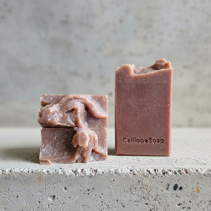 Two bars of soap on a cement surface with a neutral background