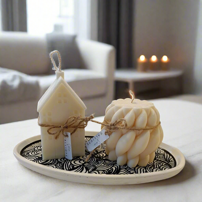 An oval, beige concrete decorative tray with cork lining, displayed with candles and decorative objects on a patterned surface.