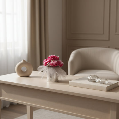 Living room with a coffee table featuring decorative items including a vase with pink flowers.