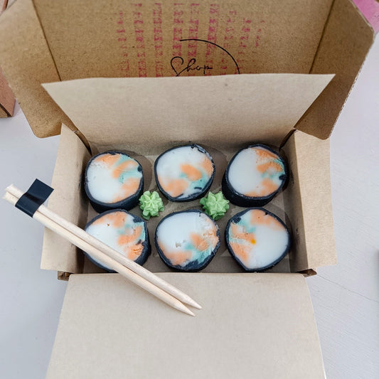 Box of decorative sushi candles with chopsticks on a white background