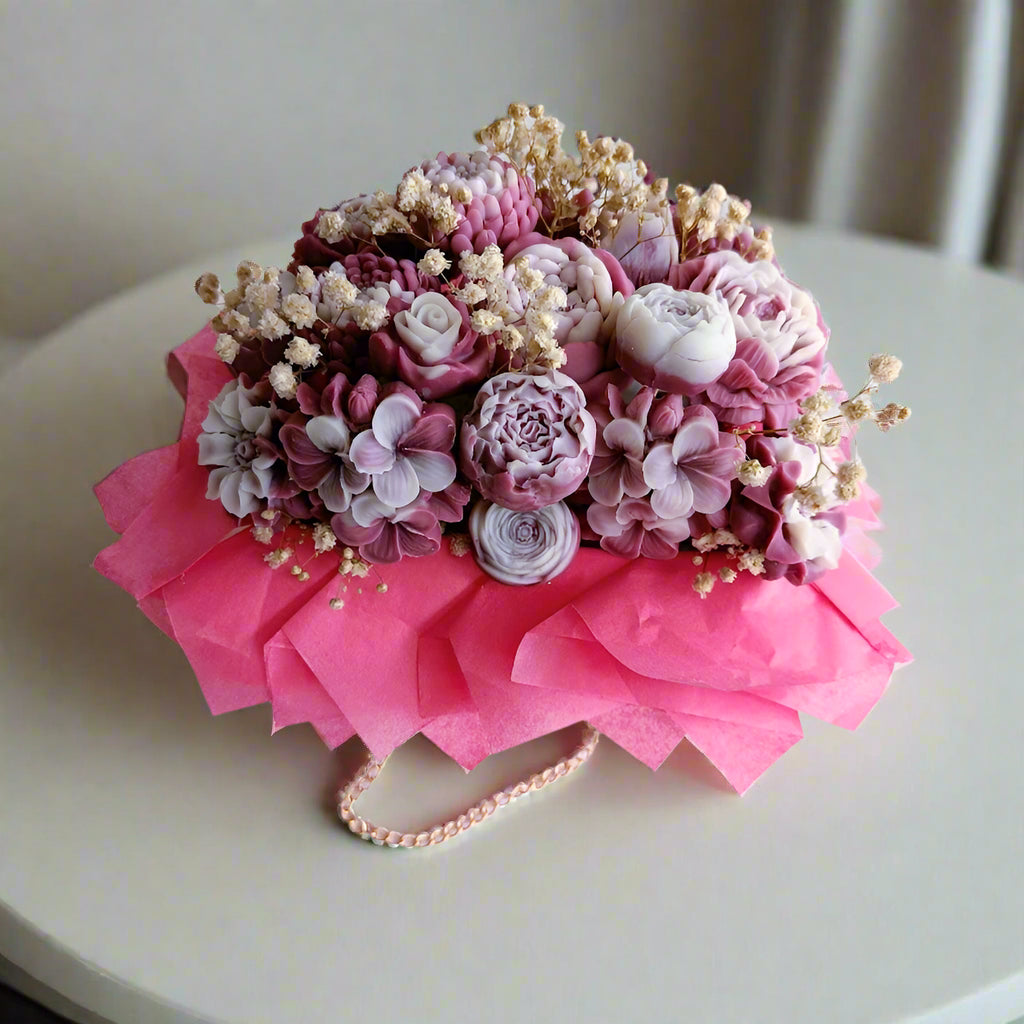 Bouquet of pink and white flowers with a pink ribbon on a white surface.