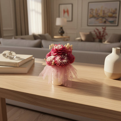 Candle bouquet in a metallic box with pink tulle, on a coffee table.