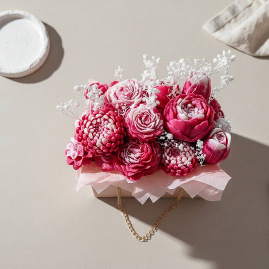 Pink flower arrangement in a box on a light surface with scissors nearby