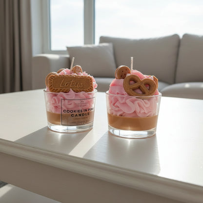 Two small glass containers with pink whipped cream, cookies, and a visible brand label on a light surface.