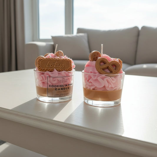 Two small glass containers with pink whipped cream, cookies, and a visible brand label on a light surface.
