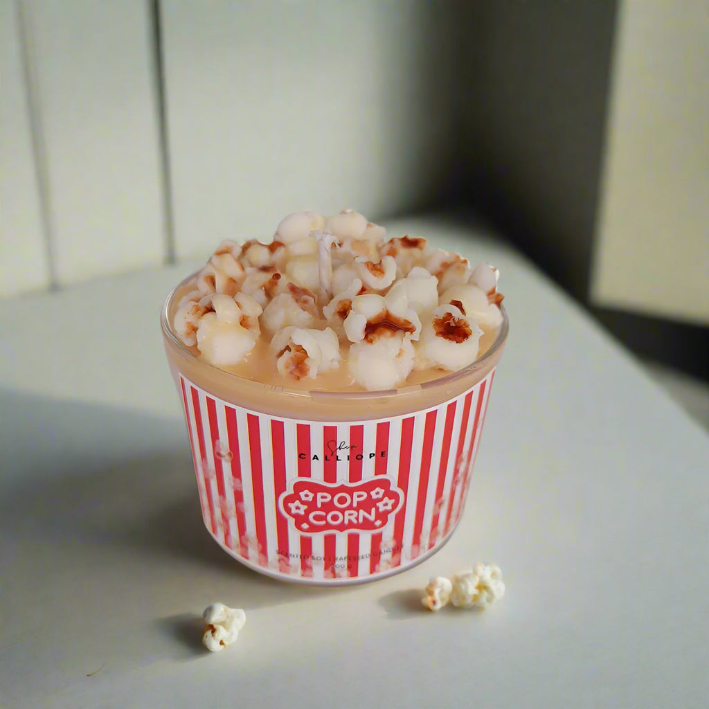 Popcorn in a red and white striped container on a light surface.
