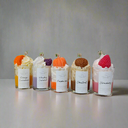 Five small glass jars with whipped cream and fruit toppings on a gray background