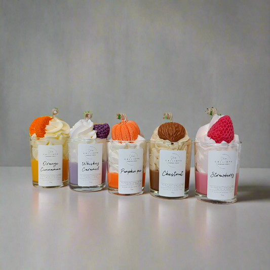 Five small glass jars with whipped cream and fruit toppings on a gray background