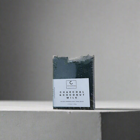 Packaged charcoal soap with coconut milk on a light gray background