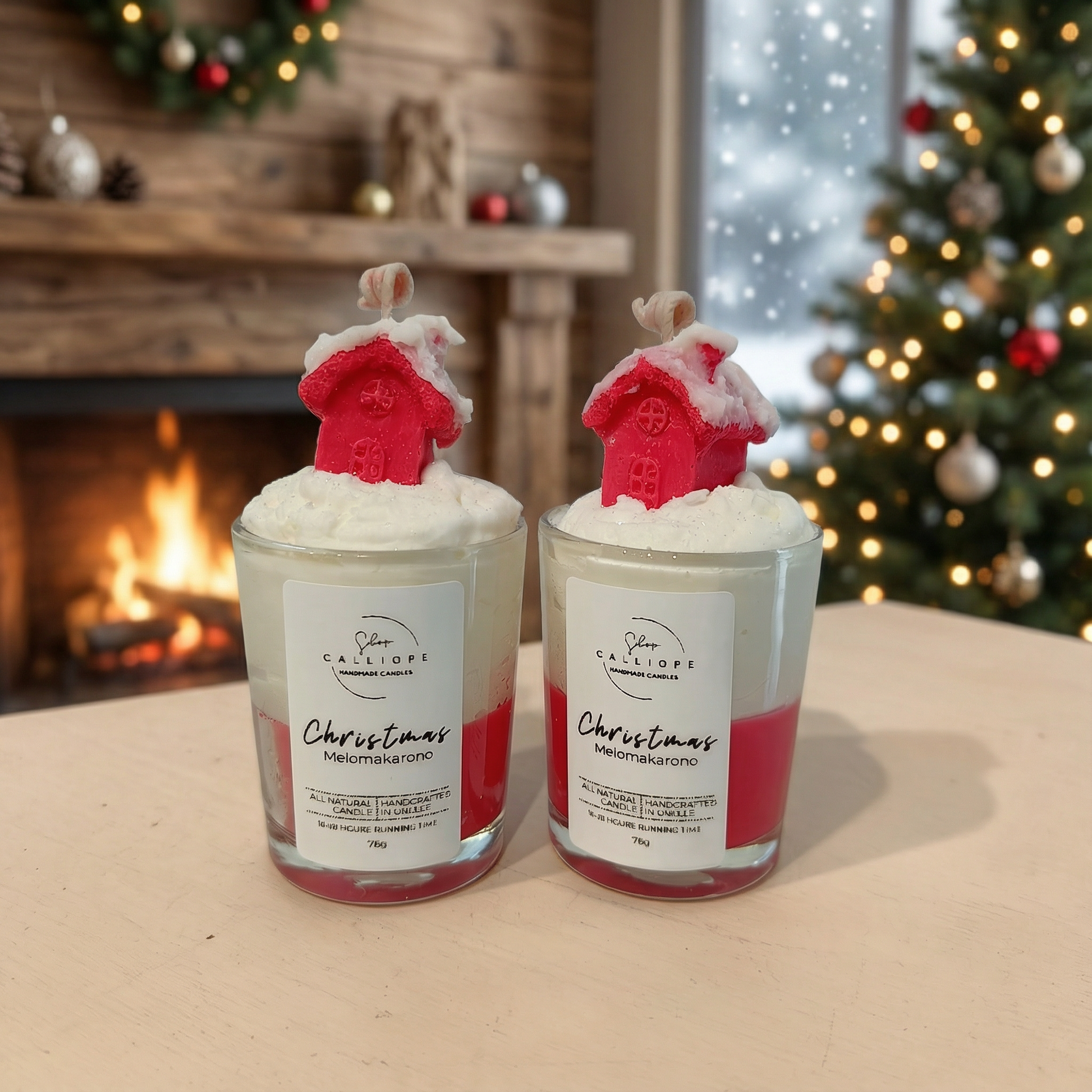 Christmas-themed candles with snowy red house design on top, surrounded by festive decorations in front of a fireplace.